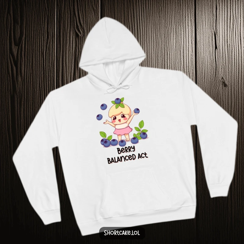Funny hoodie with a shortcake character playfully juggling blueberries, offering comfort and a touch of playful skill.